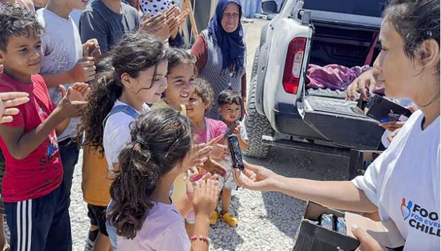 Female Volunteer giving out MREs to children at a tent city in Turkey