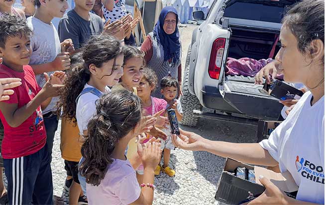 Female Volunteer giving out MREs to children at a tent city in Turkey